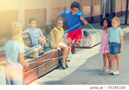 Happy smiling little friends playing with chinese jumping rope Happy smiling little friends playing with chinese jumping rope 70280100