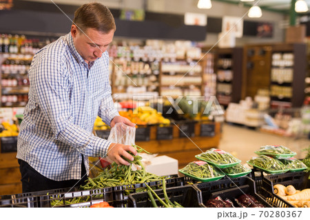 Man choosing green beans at grocery store Man choosing green beans at grocery store 70280367