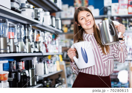 Young attractive woman choosing kettle in household appliances store 70280615