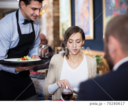 waiter man serving company at restaurant 70280617