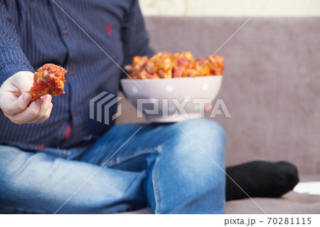 man on the couch with a plate of Buffalo Chicken Wings, copy space 70281115