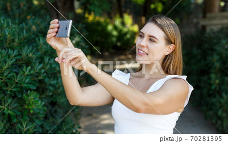Woman taking selfie in park 70281395