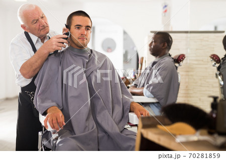 Man getting haircut from aged barber Man getting haircut from aged barber 70281859