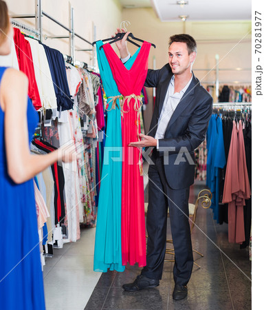 man smiling and offering dresses in women clothing store man smiling and offering dresses in women clothing store 70281977