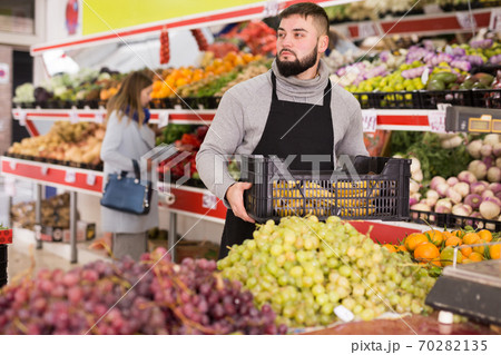 Man seller moving box of bananas in grocery shop Man seller moving box of bananas in grocery shop 70282135