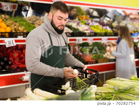 Market worker puts onions on the counter 70282754