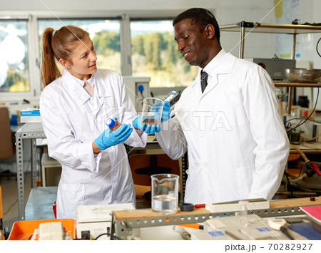 Focused lab technicians in gloves working with reagents and test tubes 70282927