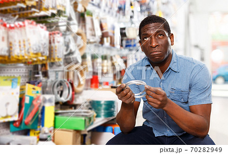salesman arranging different goods on stand in shop salesman arranging different goods on stand in shop 70282949