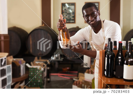 afro male seller of wine shop offering wine bottle to buy afro male seller of wine shop offering wine bottle to buy 70283403