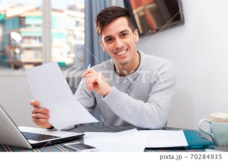 Smiling male with laptop analyzing domestic budget 70284935