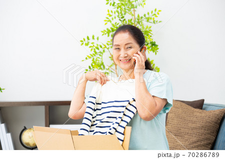 荷物が届く　お礼の電話をかけるシニア女性 70286789