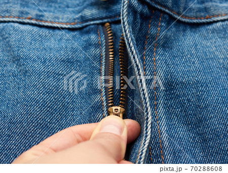 hand unzips the iron zipper on the fly of blue jeans pants hand unzips the iron zipper on the fly of blue jeans pants 70288608