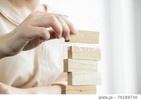Hands of businesswomen playing wooden block game. Concept Risk of management and strategy plans for business growth and success Hands of businesswomen playing wooden block game. Concept Risk of management and strategy plans for business growth and success 70289730