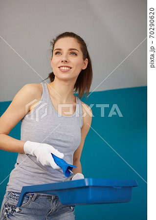 woman holding paint roller for wall painting and empty paint bucket with copy space isolated on  background. Instruments for renovation apartment room. Repair home concept 70290620