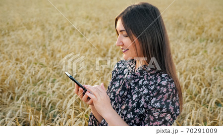 Young woman with phone in ripe wheat field in 70291009