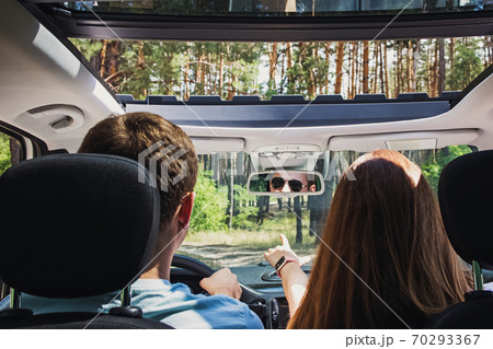 Couple in the car travelling on the road through trees. 70293367