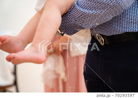baby in arms of godfather in baptism pee. funny. 70293597