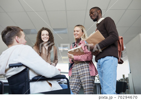Students Talking to Wheelchair User in College 70294670