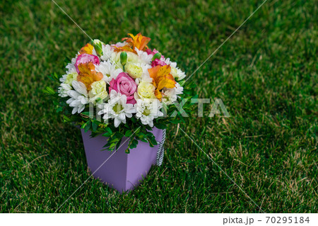 bouquet flowers in hatbox on lawn. place for text. 70295184