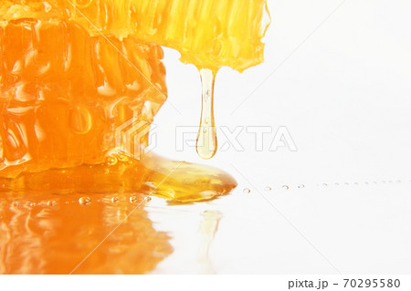 honey flowing from the honeycombs on a light background honey flowing from the honeycombs on a light background 70295580