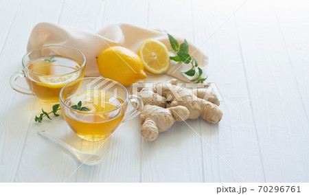 Cups of healthy ginger tea with mint leaves and lemon on white table Cups of healthy ginger tea with mint leaves and lemon on white table 70296761