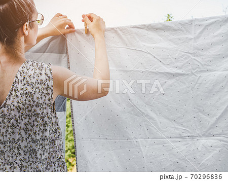 Beautiful hostess hangs bed linen. Sunny day Beautiful hostess hangs bed linen. Sunny day 70296836