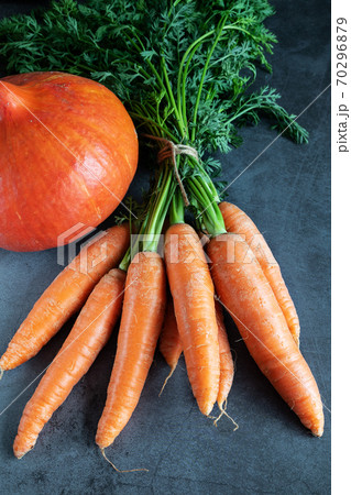 Carrots with fresh leaves and a pumpkin on dark background 70296879