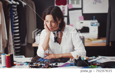 Pensive fashion designer sitting desk Pensive fashion designer sitting desk 70297635
