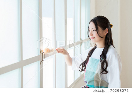 陽の光が差し込む窓の枠を掃除する主婦 70298072