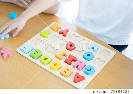 幼児教室 英語学習 アルファベットのブロックを型にはめる子供の手元の写真素材