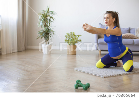 Pregnant young woman doing relaxation exercises on the floor. Pilates, yoga and a healthy lifestyle. Pregnant young woman doing relaxation exercises on the floor. Pilates, yoga and a healthy lifestyle. 70305664