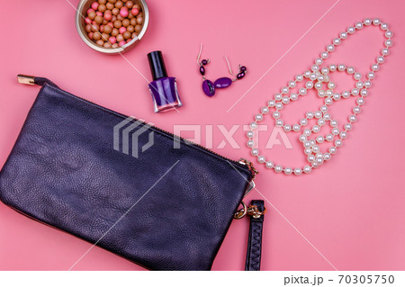 Clutch bag, pearl necklace, earrings, nail polish and rouge balls on pink background. Beauty and fashion concept. Flat lay, top view Clutch bag, pearl necklace, earrings, nail polish and rouge balls on pink background. Beauty and fashion concept. Flat lay, top view 70305750
