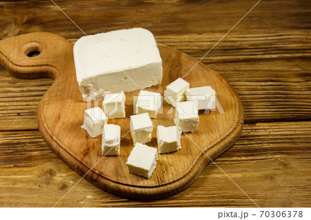 Feta cheese on cutting board on a wooden table Feta cheese on cutting board on a wooden table 70306378