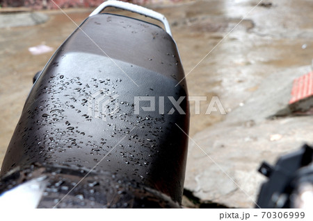 Closeup of a black motorcycle seat covered in raindrops outdoors during daylight 70306999