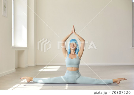 Smiling girl sitting on fitness carpet on twine and practicing stretching, yoga, pilates or meditation Smiling girl sitting on fitness carpet on twine and practicing stretching, yoga, pilates or meditation 70307520
