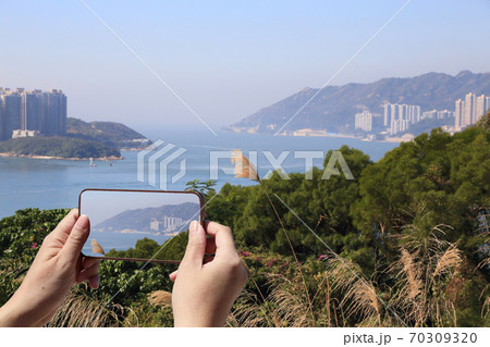 tourist taking picture of coastal landscape in Hong Kong  70309320