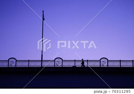 夕暮れ時の橋を歩く人 70311295