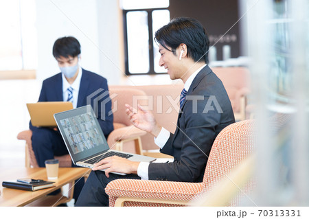 ソファーに座ってオンライン会議をする若いビジネスマン 70313331