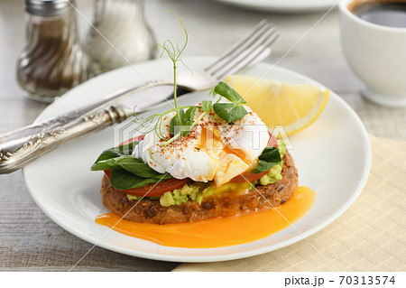 Eggs Benedict with guacamole on cereal bread 70313574