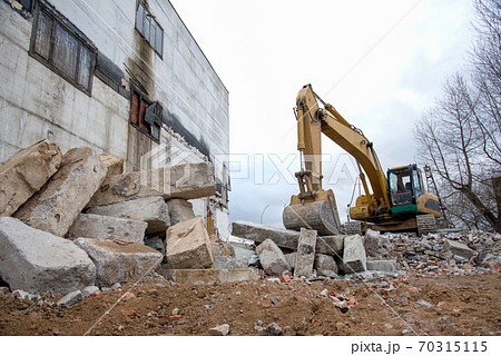 Yellow excavator with bucket at demolition of tall building. Yellow excavator with bucket at demolition of tall building. 70315115