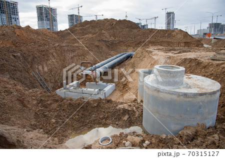 Laying heating pipes in a trench at construction site. Laying heating pipes in a trench at construction site. 70315127