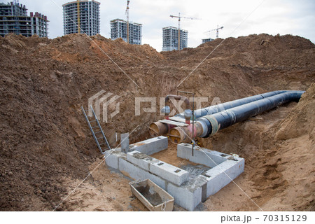 Laying heating pipes in a trench at construction site.  70315129