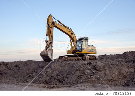 Excavator working at open pit mining on sunset background. Excavator working at open pit mining on sunset background. 70315153