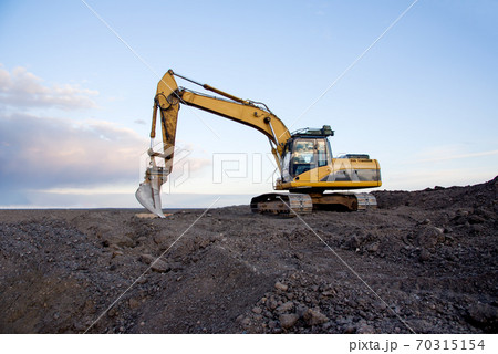 Excavator working at open pit mining on sunset background. Excavator working at open pit mining on sunset background. 70315154