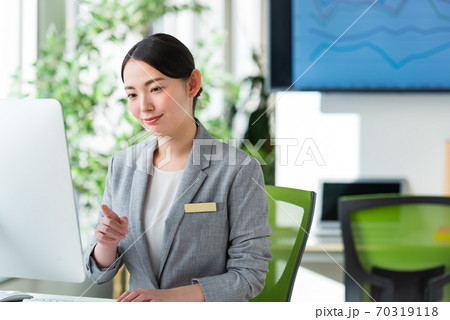 明るいオフィスの窓側でパソコン操作する若いビジネスウーマン 70319118