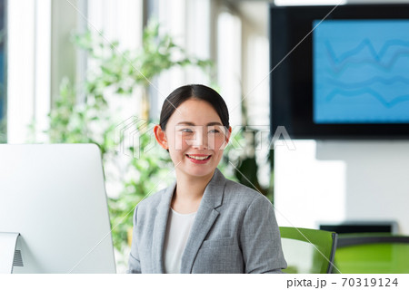 明るいオフィスの窓側でパソコン操作する若いビジネスウーマン 70319124