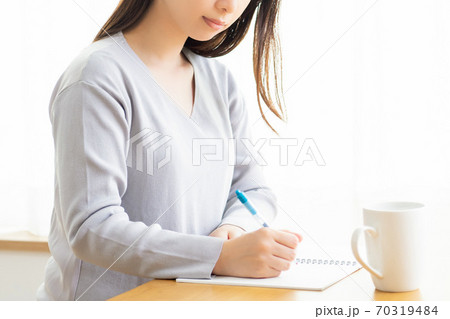 ノートにメモを書く若い女性 ノートにメモを書く若い女性 70319484