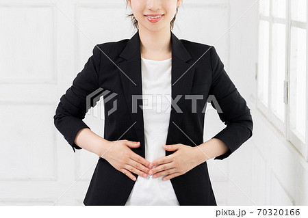 お腹に手を当てる若いビジネスウーマン 70320166