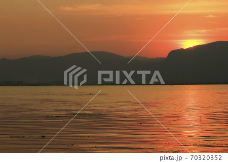 The orange light of the sunset behind the mountain 70320352