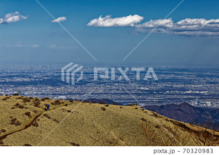 冬の丹沢・不動ノ峰付近の草原を行く登山者と東京都心の眺め 70320983